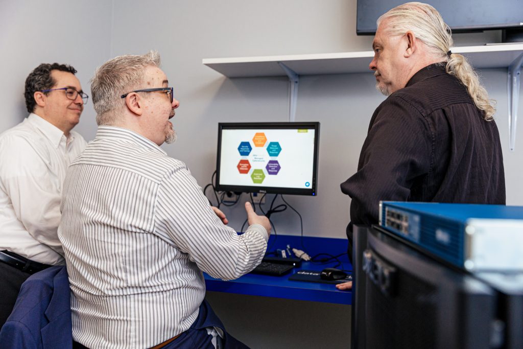 3 men talking near computer