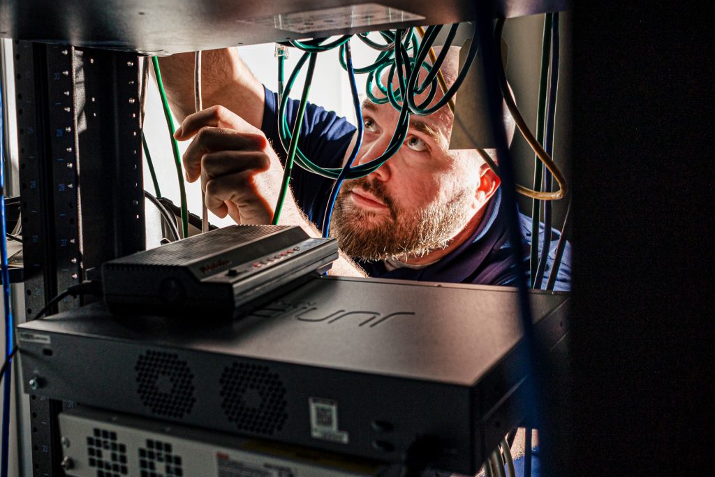 Man working in network closet.