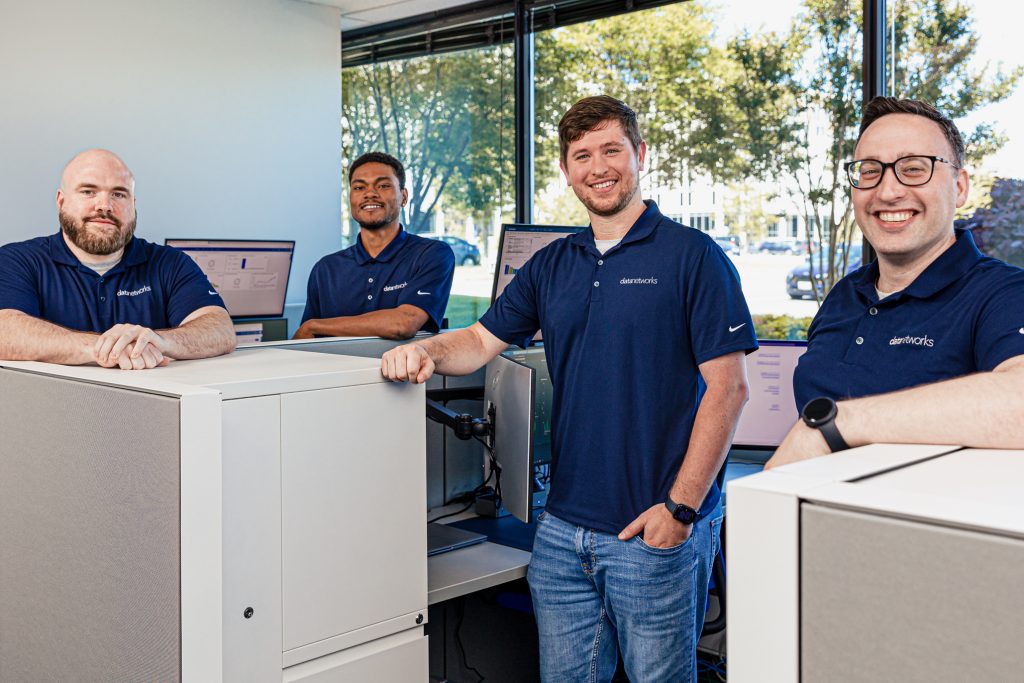 4 men standing at desks