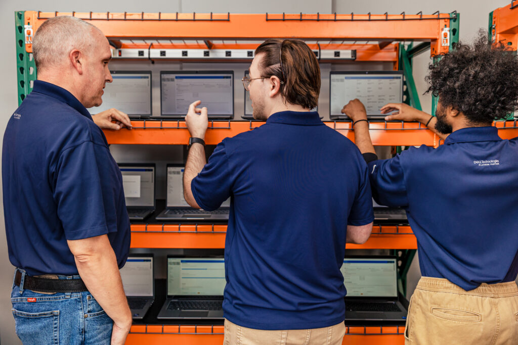 Three men performing white glove services on laptops